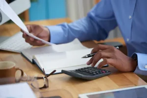 Person calculating finances with a calculator and paper, representing bookkeeping and accounting tasks for a startup business